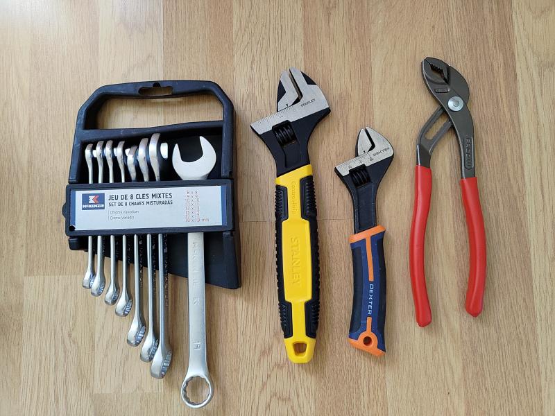 Photographie d'un jeu de clés mixtes, de deux clés à molette de tailles différentes et d'une pince multiprise.